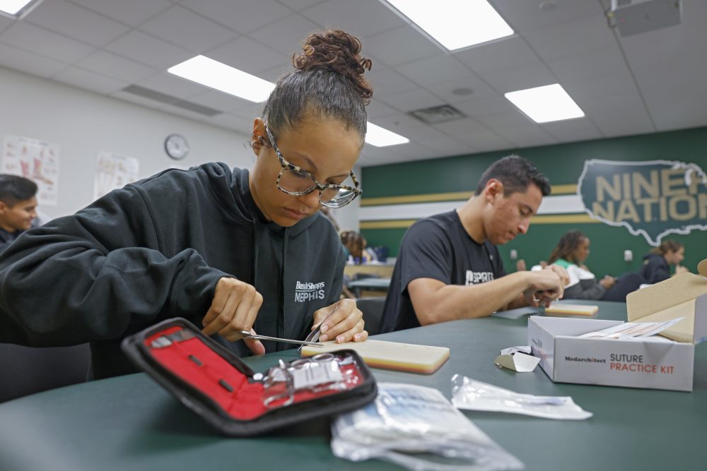 Female athletic training student uses a practice suture kit