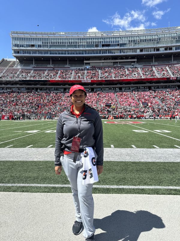 Female athletic trainer standing on the field of a full stadium