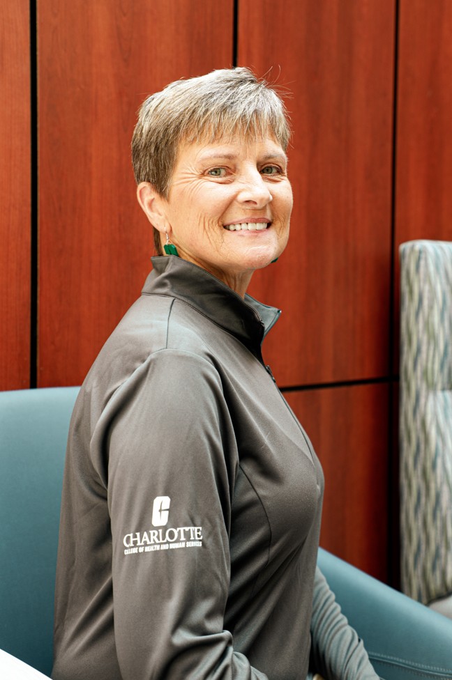 Woman in grey shirt smiling at the camera